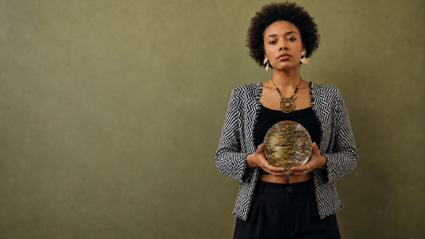 Model holding a large polished golden rutilated quartz sphere